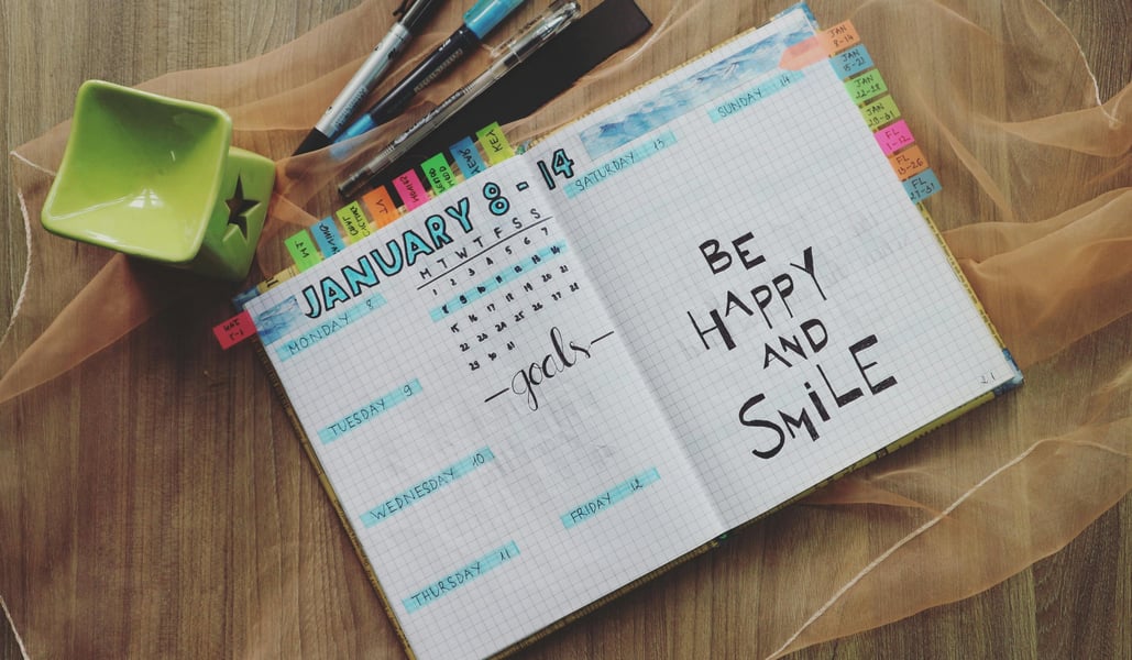 Colorful open calendar with ‘Be Happy and Smile’ written inside, surrounded by pens, symbolizing joyful planning, positivity, and mindful living Colorful open calendar with ‘Be Happy and Smile’ written inside, surrounded by pens, symbolizing joyful planning, positivity, and mindful living