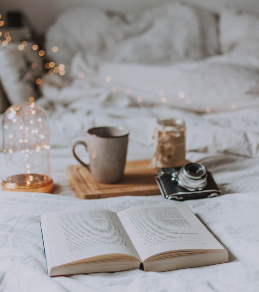 Open book on cozy bed surrounded by tea, candle, and camera, capturing moments of inspiration, rest, and personal growth through reading Open book on cozy bed surrounded by tea, candle, and camera, capturing moments of inspiration, rest, and personal growth through reading